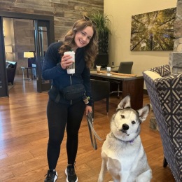 resident with a cup of coffee and her dog in leasing office